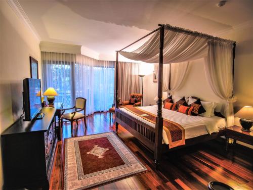a bedroom with a canopy bed and a television at Angkor Palace Resort & Spa in Siem Reap