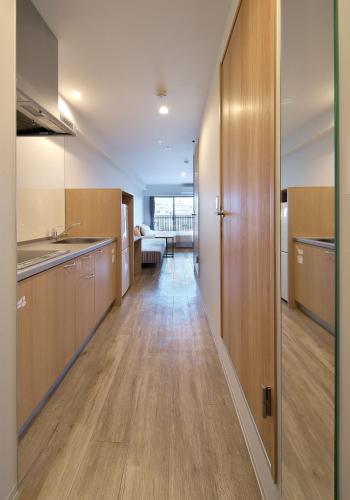 a kitchen with wooden cabinets and a long hallway at e-stay ebisu in Osaka