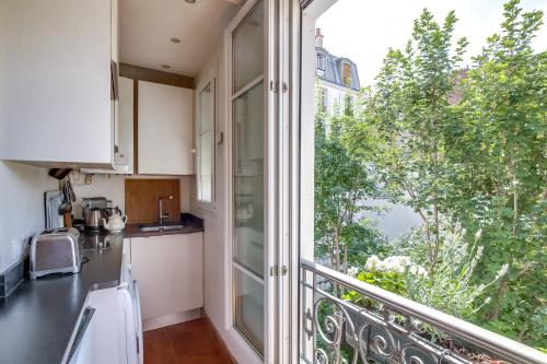 Il comprend une cuisine avec un balcon et une grande fenêtre. dans l'établissement Apartment Tour Eiffel by Weekome, à Paris