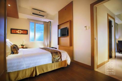 a hotel room with a bed and a television at The Malibu Suites Balikpapan by Sissae Living in Balikpapan