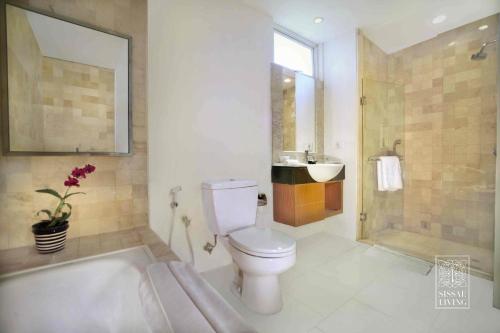 a bathroom with a tub and a toilet and a sink at The Malibu Suites Balikpapan by Sissae Living in Balikpapan