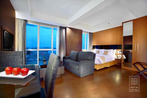 a hotel room with a bed and a chair and a table at The Malibu Suites Balikpapan by Sissae Living in Balikpapan
