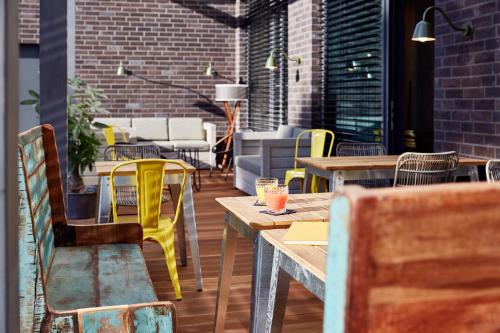 a restaurant with wooden tables and yellow chairs at Me and All Hotel Mainz, by Hyatt in Mainz