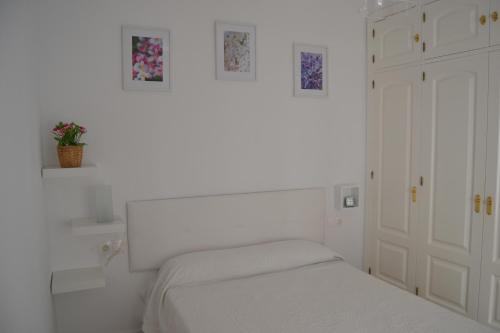 een witte slaapkamer met een bed en enkele foto's aan de muur bij Beautiful Central Cadiz in Cádiz