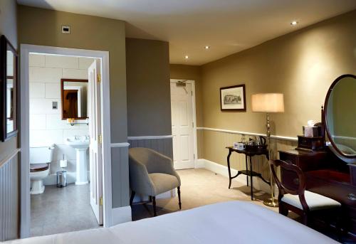 a bedroom with a bathroom with a sink and a mirror at The Golden Pheasant in Knutsford