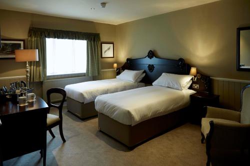 a hotel room with two beds and a desk and a chair at The Golden Pheasant in Knutsford