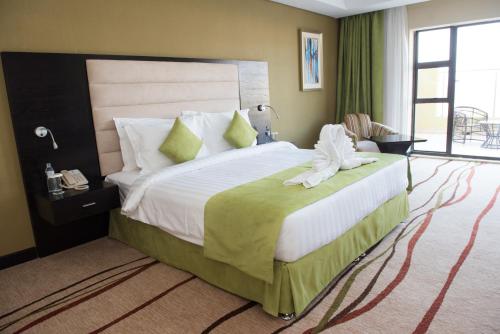 a hotel room with a large bed with green curtains at Crossroads Hotel Blantyre in Blantyre