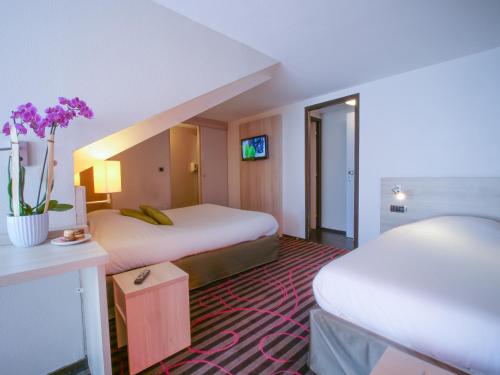 a hotel room with two beds and purple flowers at Hôtel Inn Design Resto Novo Sablé in Sablé-sur-Sarthe