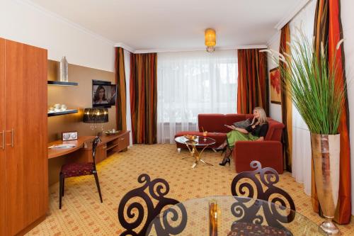 a woman sitting in a red chair in a living room at Thermalhotel Gass in Bad Füssing