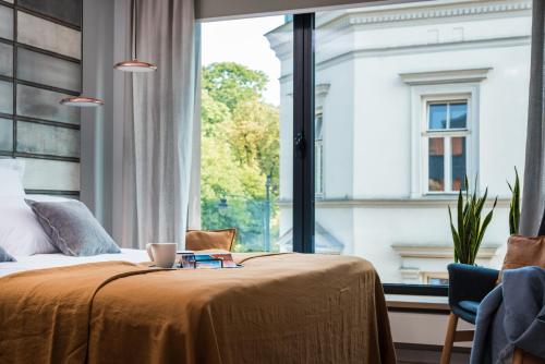 um quarto com uma cama e uma grande janela em Academia Apartments em Cracóvia