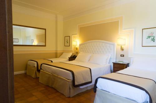 ein Hotelzimmer mit 2 Betten und einem Spiegel in der Unterkunft Parco del Lago Resort & SPA in Villagrande