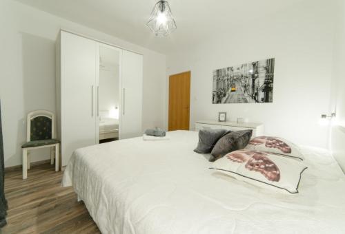 a white bedroom with a large white bed with pillows at Villa Lucija in Gruda