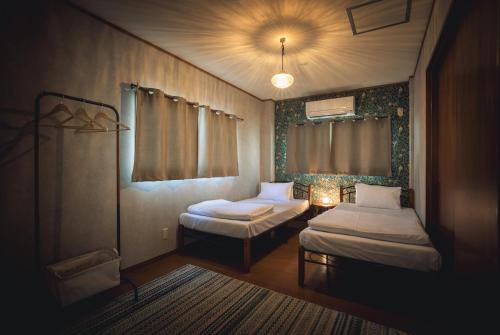 松山市にある3LDK 田家のベッド2台と窓が備わる小さな客室です。