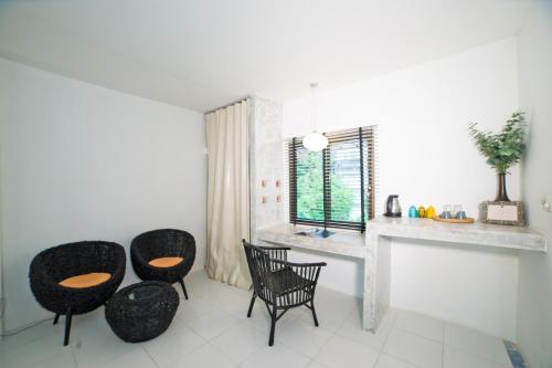 a kitchen with three chairs and a table and a window at Surintra Boutique Resort in Surin Beach