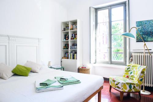 a white bedroom with a bed and a chair at Little Garden House in Cernobbio