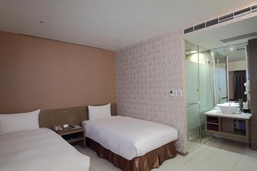 a hotel room with two beds and a bathroom at Nest Hotel in Kaohsiung