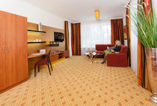 a woman sitting on a couch in a hotel room at Thermalhotel Gass in Bad Füssing