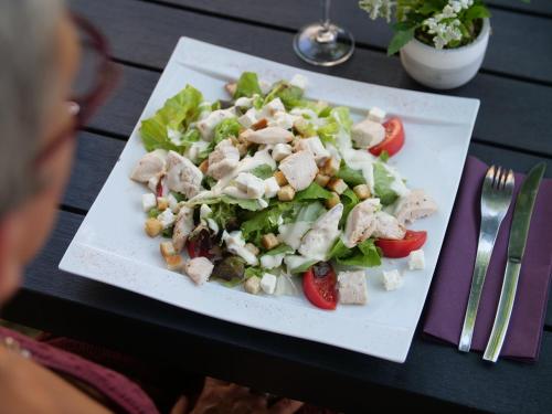 a white plate with a salad on a table at Hôtel Inn Design Resto Novo Le Mans in Arnage