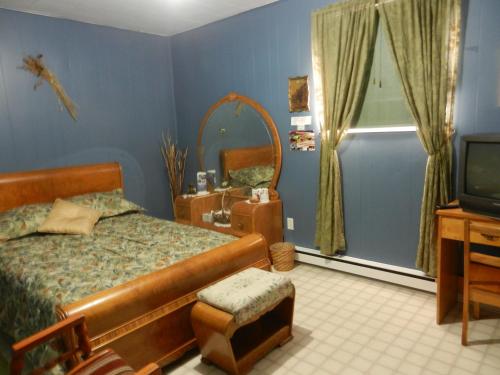 - une chambre avec un lit, un miroir et une télévision dans l'établissement Domaine Joseph Ross Bed and Breakfast, à Cap-Chat