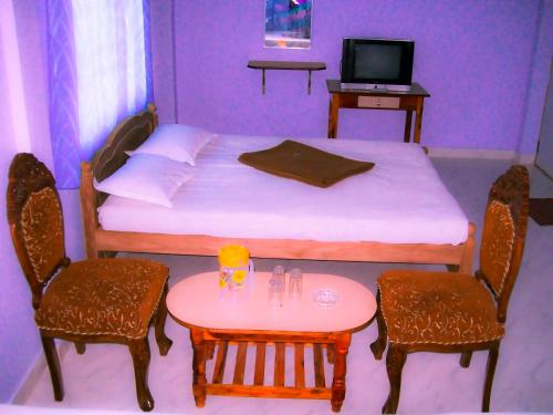 a bedroom with a bed and two chairs and a table at Aruvi Hotel in Yelagiri
