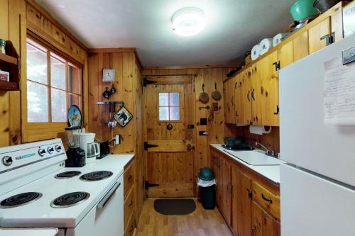 uma cozinha com um fogão branco e armários de madeira em Traditional Maine Cabin em Greenville