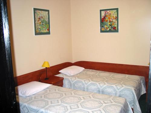 ワルシャワにあるNoclegi Ufoのベッド2台付きの部屋、壁に2枚の写真が飾られています。