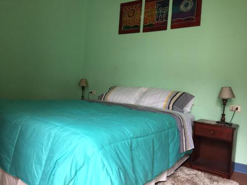 1 dormitorio con 1 cama con manta azul y 2 lámparas en Casa conferencia, en Santiago