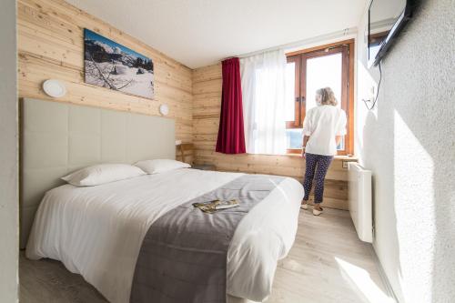 Una mujer mirando por una ventana en un dormitorio en Arc en Ciel Les Karellis Vacances Bleues- Ski Pass Inclus, en Montricher-le-Bochet
