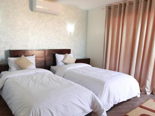 two beds in a hotel room with white sheets at Dakhla Kitesurf World in Dakhla