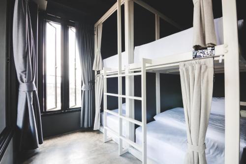 a bedroom with two bunk beds and a window at Issara by D Hostel in Bangkok