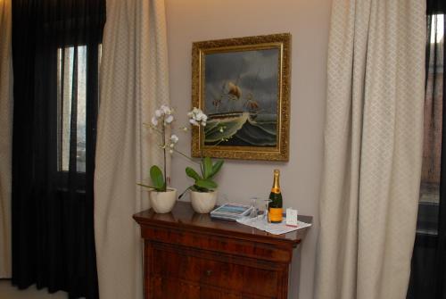 a table with a bottle of wine and a painting on the wall at Hotel Excelsior in La Maddalena
