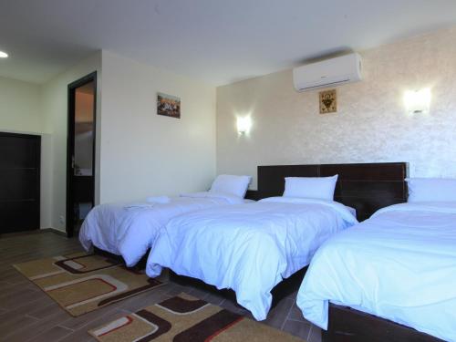 three beds in a room with white sheets at Dakhla Kitesurf World in Dakhla