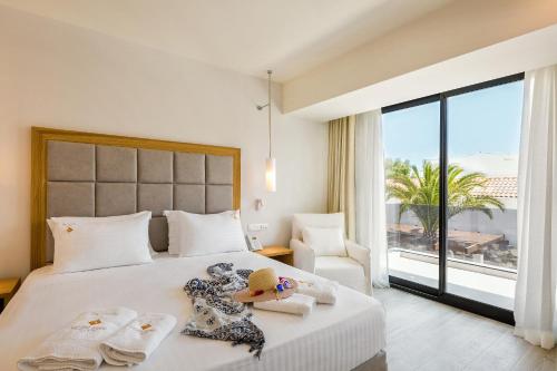 a bedroom with a large bed with a large window at Samian Mare Hotel, Suites & Spa in Karlovasi