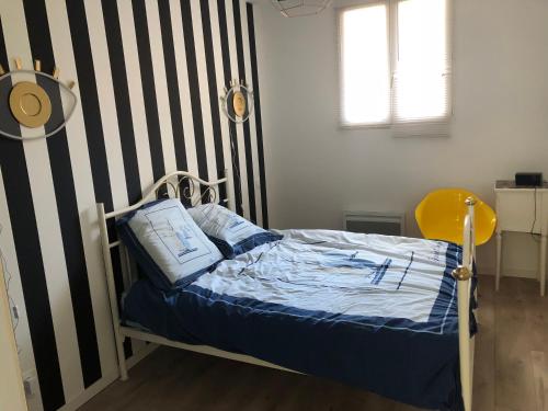 a bedroom with a bed with a striped wall at Le Riva Plage Appartement in Ouistreham