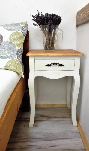 a nightstand with a vase on it next to a bed at Penzion Krakovice in Kaplice