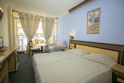 エレニテにあるAtrium Beach Hotel - All Inclusiveのベッド、テーブル、椅子が備わるホテルルームです。