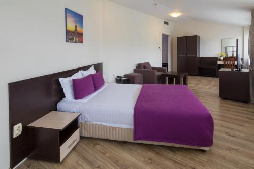 a bedroom with a large bed with purple sheets at Hotel Kardjali in Kŭrdzhali