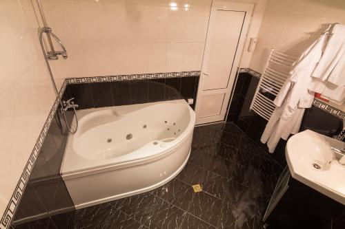 a bathroom with a bath tub and a sink at Hotel Kardjali in Kŭrdzhali