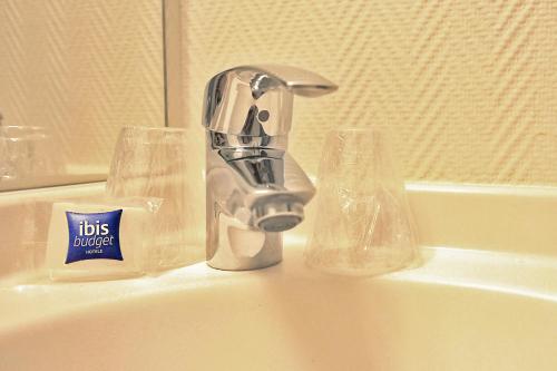 um lavatório com uma torneira e dois copos em Hotel ibis Budget Laval em Bonchamp-lès-Laval