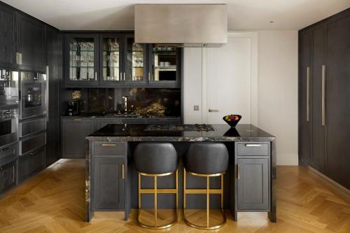 a kitchen with black cabinets and a island with bar stools at Four Seasons Hotel London at Tower Bridge in London