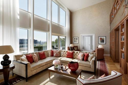 a living room with a large couch and windows at Four Seasons Hotel London at Ten Trinity Square in London