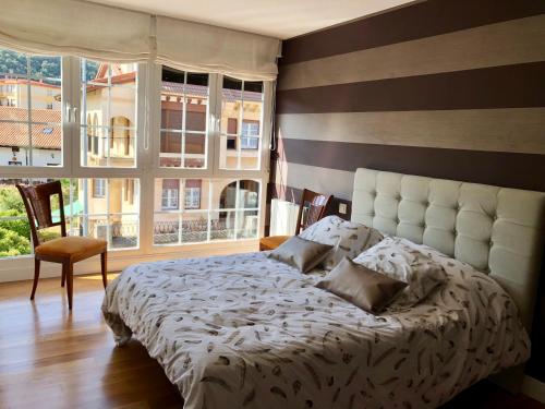 a bedroom with a large bed and two windows at Chalet en Espinosa Monteros in Espinosa de los Monteros