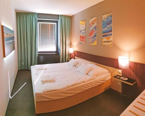 a bedroom with a large bed with white sheets at Orion Apartman in Sárvár