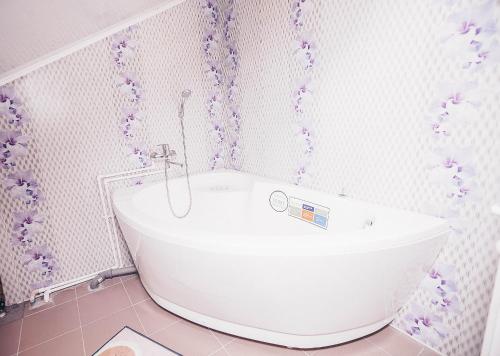チェレポヴェツにあるNa naberezhnoy Guesthouseのピンクのバスルーム(紫色の花の白いバスタブ付)