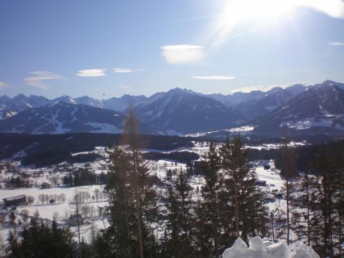a view of a snowy mountain with the sun in the sky at Pension Trillerhof in Ramsau am Dachstein