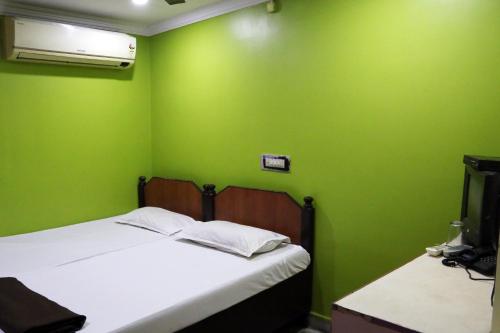 a green room with a bed and a television at Vani Lodge in Visakhapatnam