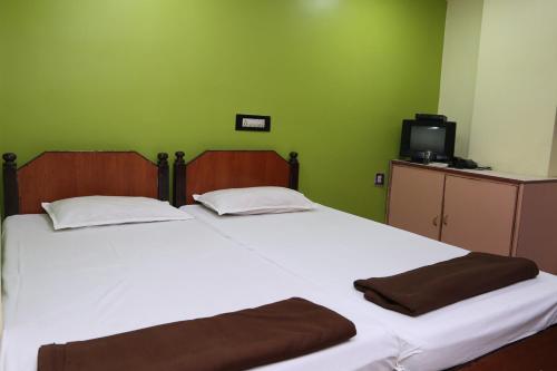 two beds in a room with a green wall at Vani Lodge in Visakhapatnam