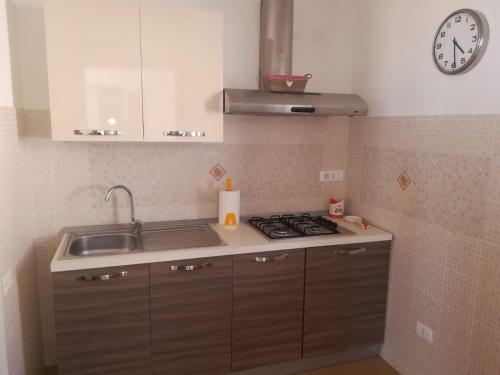a kitchen with a sink and a stove and a clock at Mare d'Amuri in Porto Empedocle