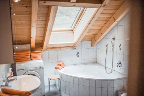 uma casa de banho com uma banheira e uma máquina de lavar roupa em Ferienparadies Hugenhof em Simonswald