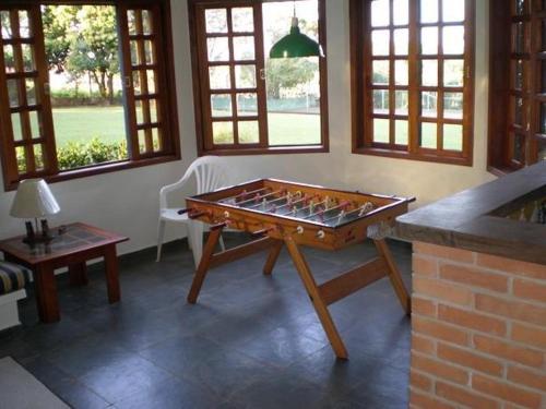 a living room with a table in a room with windows at Casa De Campo Boituva in Boituva